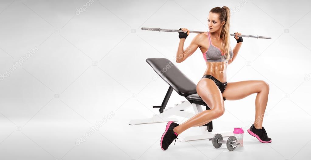 Nice sexy woman sitting on a bench and doing workout with dumbbell