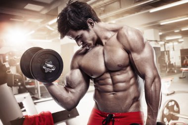 kaslı vücut geliştirmeci biri dumbbells ile yapıyor