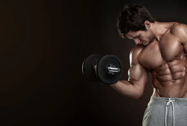 Muscular bodybuilder guy doing exercises with dumbbells — Stock Photo, Image