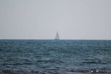 Ufuk çizgisinin ortasında bulutlu gökyüzü olan bir tekne.