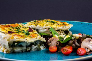Çam fıstığı ve erimiş peynirli vejetaryen lazanyası. Salata ve kırmızı şarapla.