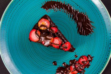 Çilekli çikolatalı pasta turkuaz tabakta, yakın plan.