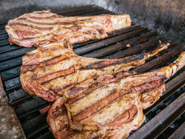 Tomahawk bifteği alevli, siyah ızgarada.