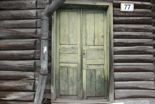 La vecchia porta di legno verde della vecchia casa di tronchi e scarico dell'acqua — Foto Stock