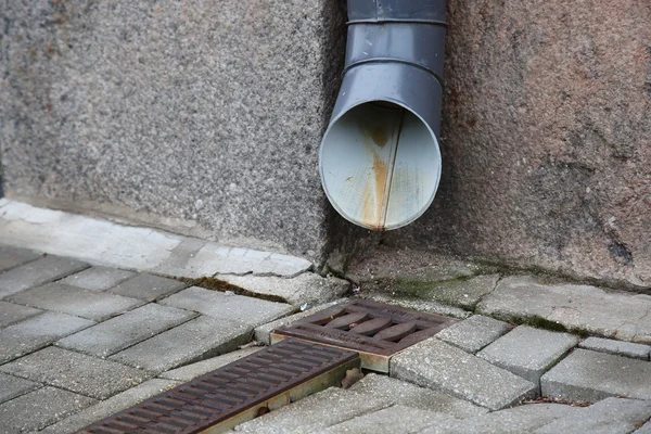 Water afvoer in de buurt van de muur op de straat — Stockfoto