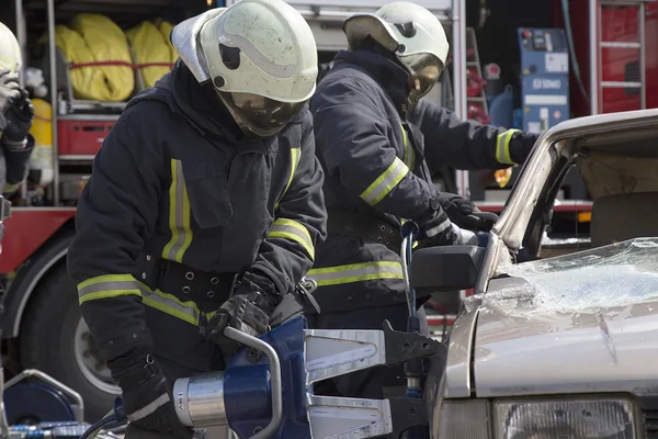 Bombeiros com as tesouras pneumáticas abrir as portas do carro — Fotografia de Stock