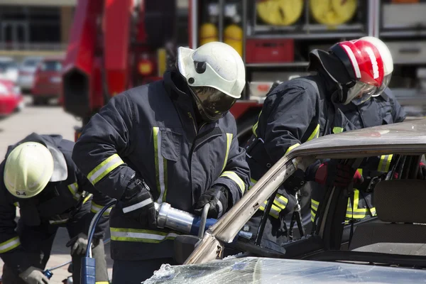 Bombeiros com as tesouras pneumáticas abrir as portas do carro — Fotografia de Stock