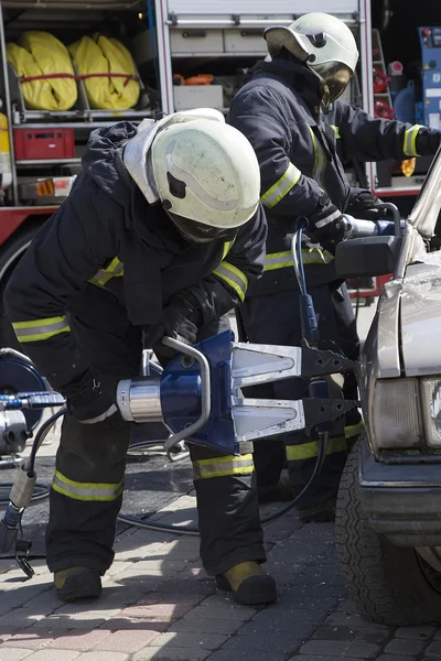 Bombeiros com as tesouras pneumáticas abrir as portas do carro — Fotografia de Stock