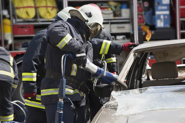 Firefighters with the pneumatic shears open the car doors Royalty Free Stock Photos