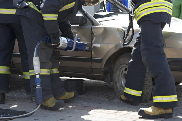 Firefighters with the pneumatic shears open the car doors Stock Photo