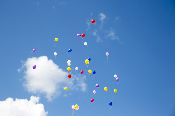 Летят разноцветные шары в голубом небе
