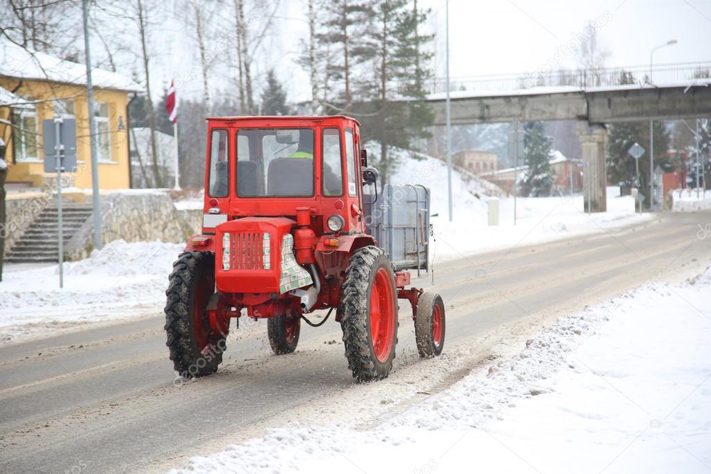 tractor driving down a snow covered road
