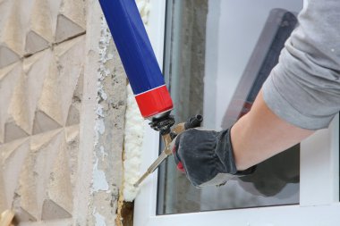 Worker's hand fix a window by  polyurethane foam clipart