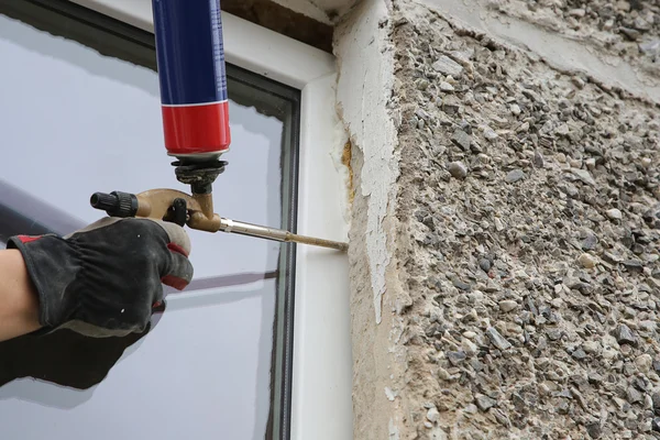 La mano del trabajador fijan la ventana por la espuma de poliuretano —  Fotos de Stock