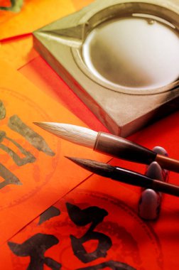 Kırmızı kağıt ve boya fırçalarında geleneksel Çin kaligrafisi.