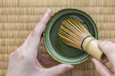 Elinde kil kap ve çırpı tutan kadının kırpılmış görüntüsü.