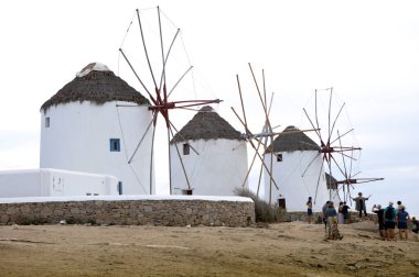 tourists in front of famous white windmills of Santorini, Greece