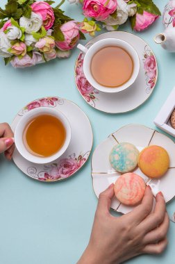 Mavi arka planda badem kurabiyesi olan bir fincan çay.