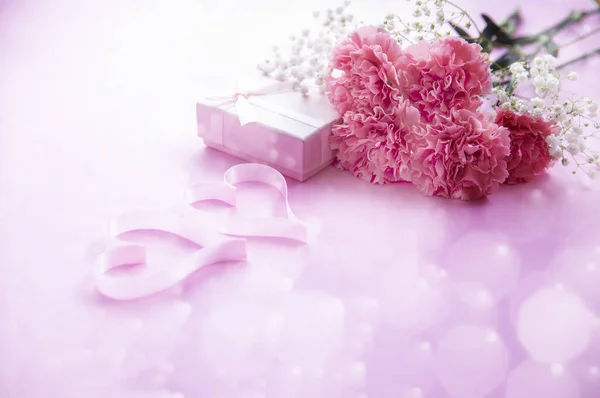 ピンクの背景に美しいピンクのカーネーションとハートの装飾品とギフトボックス — ストック写真