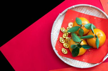 Kırmızı arka planda mandalina ve Çin sikkeleri. Refah kavramı 