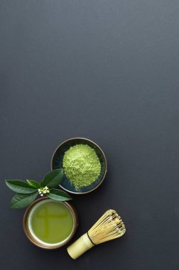 Bir fincan sıcak kibrit çayı, kasede kibrit tozu ve beyaz arka planda bambu çırpısı.