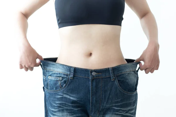 女人展示她的旧牛仔裤尺寸较大 以显示她在减肥方面的进展 — 图库照片