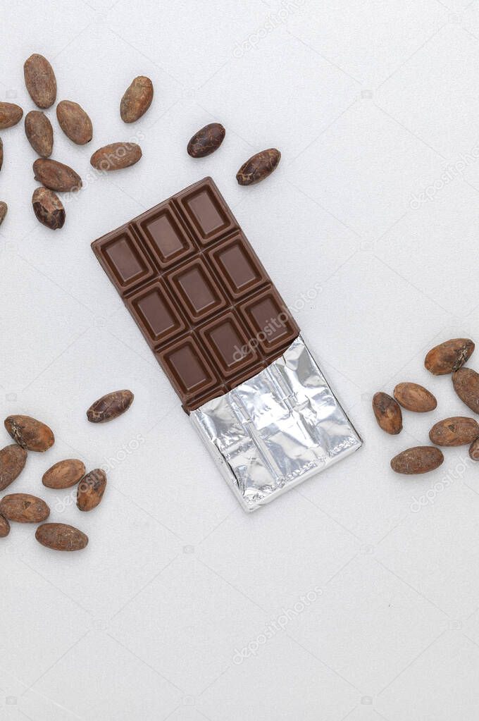 dark chocolate bar and cocoa beans on a white background. top view, copy space