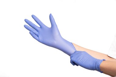 Adamın elleri menekşe lateks eldiven takıyor. Beyaz arka planda, mükemmel uyum sağlamak için diğer tarafı çekiyor.