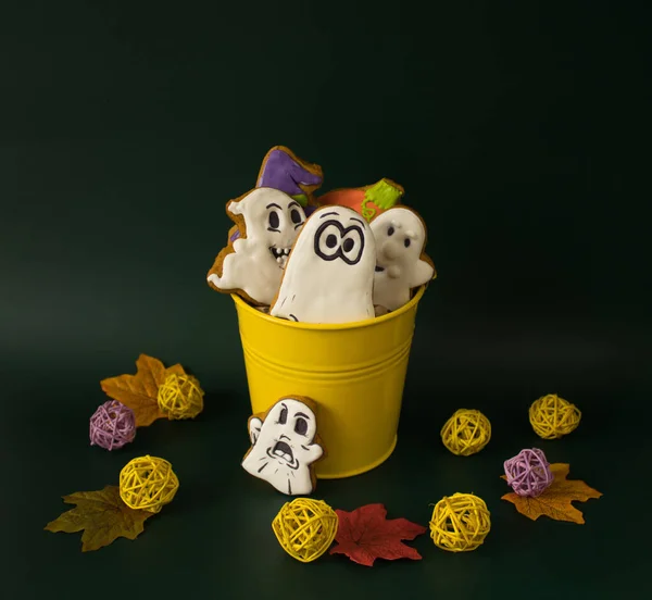 A bucket filled with gingerbreads in the form of ghosts and pumpkins as sweet presents for children on Halloween party.  Concept of preparation for the celebration of Halloween.
