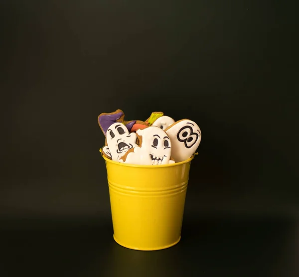 Cadılar Bayramı partisinde çocuklara hediye olarak içi zencefilli ekmek ve balkabağı dolu sarı bir kova. Cadılar Bayramı kutlaması için hazırlık kavramı. Boşluğu kopyala