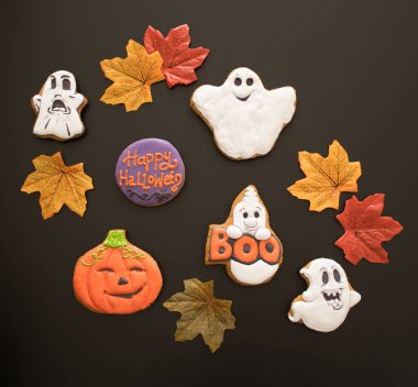 Cadılar Bayramı 'nda çocuklar için tatlı hediyeler olarak taze pişmiş ve renkli zencefilli kurabiye ve balkabağı şeklinde. Siyah arka plan. Cadılar Bayramı kutlamasına hazırlanma konsepti.