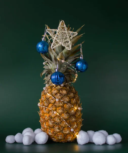 Yeşil zemin üzerinde ananas, top, yıldız ve yapay kartopları olan minimalist noel dekorasyonu konsepti. Boşluğu kopyala