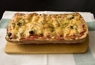 Ev yapımı bruschetta / pizza sosis, domates, zeytin, peynir ve baharatlarla pamuk havlunun üzerinde eski bir tahta üzerinde. Basit ve lezzetli yemekler. 