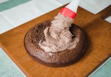 Evde kek pişirme süreci. Ev işleri işte. Taze bir ev yapımı kek ahşap bir tahtanın üzerinde. İki sünger keki, bir krema tabakası, çikolatalı ganache. Adım adım tarifli fotoğraf serileri