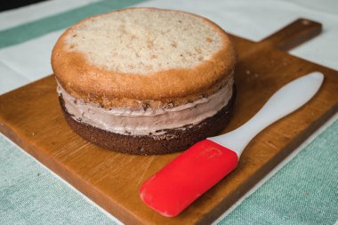 Evde kek pişirme süreci. Ev işleri işte. Taze bir ev yapımı kek ahşap bir tahtanın üzerinde. İki sünger keki, bir krema tabakası, çikolatalı ganache. Adım adım tarifli fotoğraf serileri