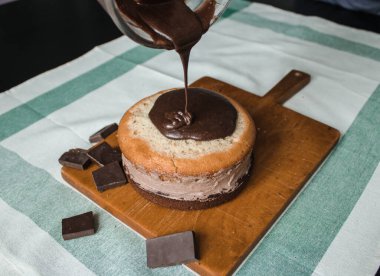 Evde kek pişirme süreci. Ev işleri işte. Taze bir ev yapımı kek ahşap bir tahtanın üzerinde. İki sünger keki, bir krema tabakası, çikolatalı ganache. Adım adım tarifli fotoğraf serileri