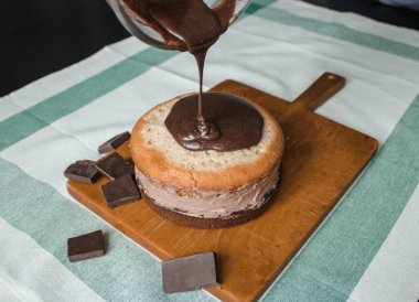 Evde kek pişirme süreci. Ev işleri işte. Taze bir ev yapımı kek ahşap bir tahtanın üzerinde. İki sünger keki, bir krema tabakası, çikolatalı ganache. Adım adım tarifli fotoğraf serileri