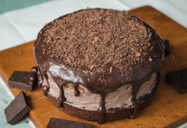 Taze bir ev yapımı kek ahşap bir tahtanın üzerinde. İki sünger keki ve aralarında çikolata ganache ve rendelenmiş acı çikolatayla kaplı bir krema tabakası. Evde kek pişirme süreci. Adım adım tarifli fotoğraf serileri