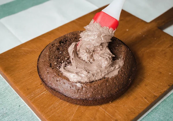 Evde kek pişirme süreci. Ev işleri işte. Taze bir ev yapımı kek ahşap bir tahtanın üzerinde. İki sünger keki, bir krema tabakası, çikolatalı ganache. Adım adım tarifli fotoğraf serileri