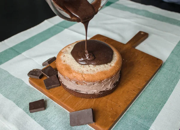 Evde kek pişirme süreci. Ev işleri işte. Taze bir ev yapımı kek ahşap bir tahtanın üzerinde. İki sünger keki, bir krema tabakası, çikolatalı ganache. Adım adım tarifli fotoğraf serileri