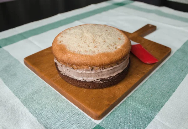 Evde kek pişirme süreci. Ev işleri işte. Taze bir ev yapımı kek ahşap bir tahtanın üzerinde. İki sünger keki, bir krema tabakası, çikolatalı ganache. Adım adım tarifli fotoğraf serileri