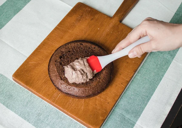 Genç bayan evde küçük bir pasta hazırlıyor. İki sünger keki ve aralarında krema katmanı, rendelenmiş acı çikolatalı çikolata ganacından oluşuyor. Evde kek pişirme süreci. Adım adım tarifli fotoğraf serileri