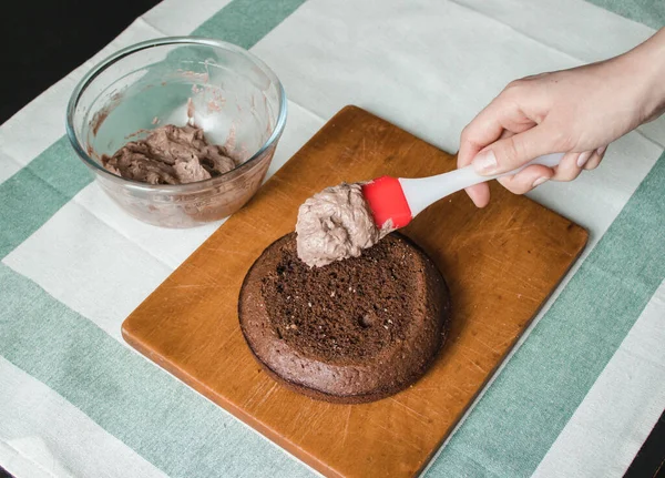 Genç bayan evde küçük bir pasta hazırlıyor. İki sünger keki ve aralarında krema katmanı, rendelenmiş acı çikolatalı çikolata ganacından oluşuyor. Evde kek pişirme süreci. Adım adım tarifli fotoğraf serileri