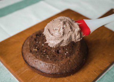 Evde kek pişirme süreci. Ev işleri işte. Taze bir ev yapımı kek ahşap bir tahtanın üzerinde. İki sünger keki, bir krema tabakası, çikolatalı ganache. Adım adım tarifli fotoğraf serileri