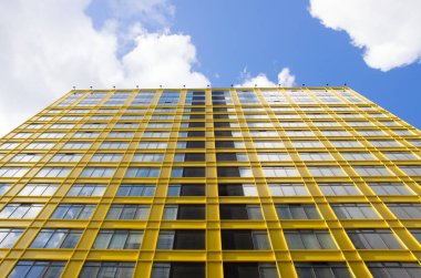 Güzel sarı bina ve bulutlu gökyüzü. Modern apartman dairesi konsepti. Açık hava yerleşim tesisi. Modern mimarinin düşük açılı görüntüsü