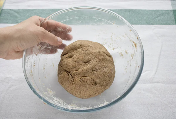 Bir kadının eli cam bir kâseyi taze ekmek hamuruyla tutuyor. Ev yapımı ekmek. Adım adım tarif. 