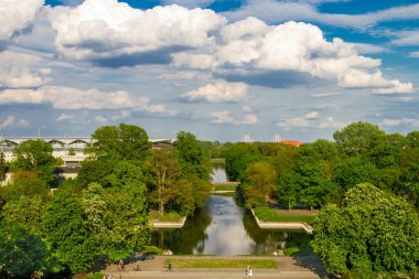 Göl ve yeşil ağaçlı park manzarası. Gökyüzü görünüyor...