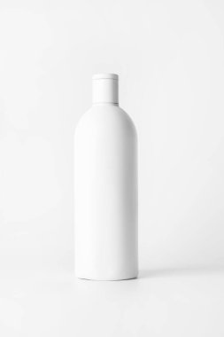 Arka planda şampuan olan beyaz bir şişe...