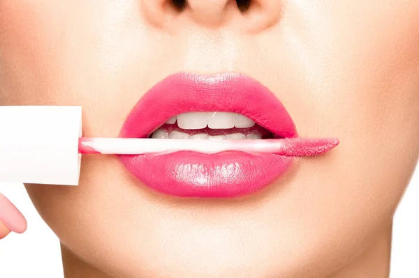 Girl lips with pink lipstick. In the mouth, an applicator for applying lipstick..