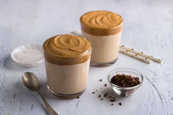 Two glasses with Dalgona coffee, cold cocktail with whipped coffee foam, popular trending drink on a light textured background